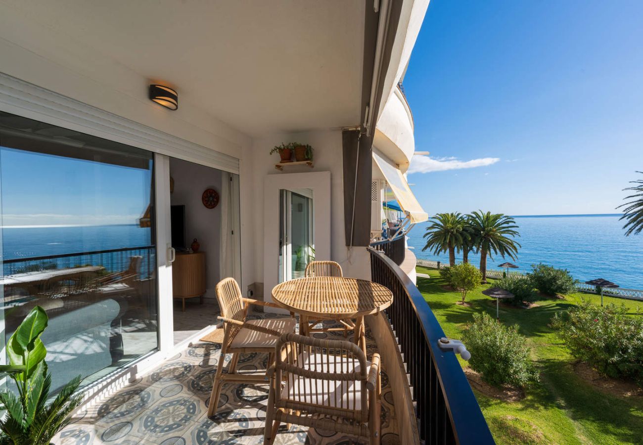 Balcone dell'alloggio con cielo soleggiato e vista sul mare e sul giardino