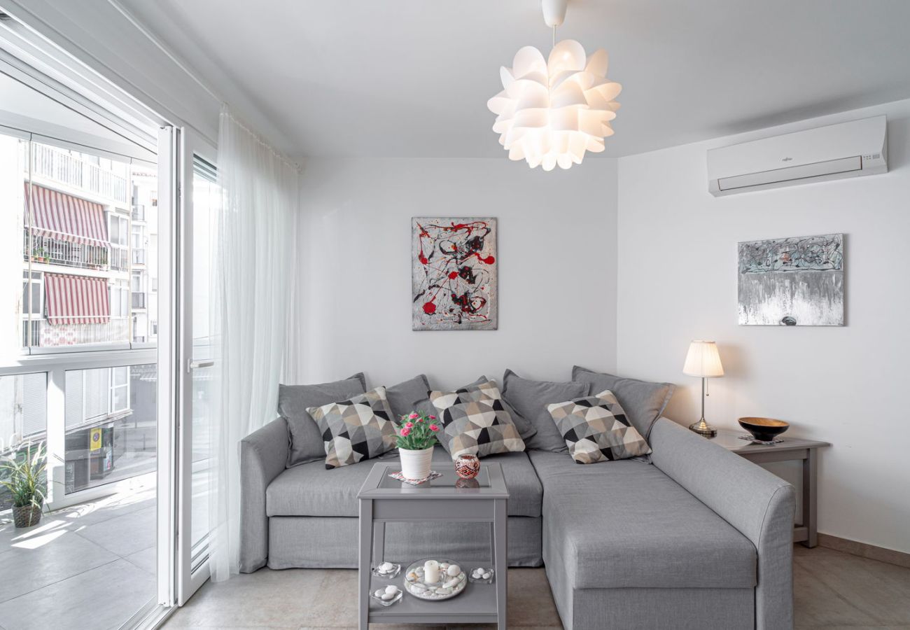 Soggiorno luminoso con divano di design e accesso diretto al balcone vetrato nel centro di Nerja.