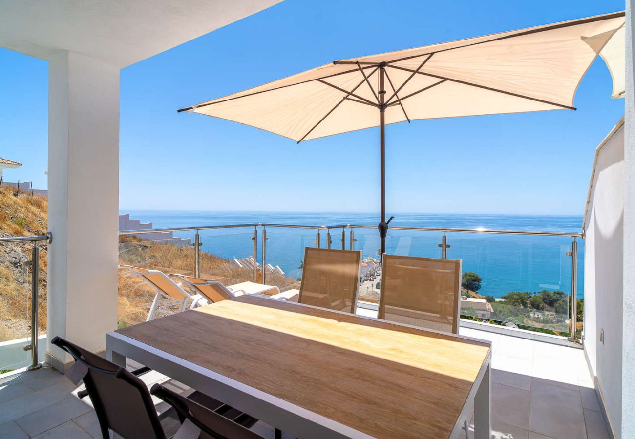 Terrazza privata con tavolo da pranzo e vista panoramica sul Mediterraneo in una giornata di sole a Nerja.